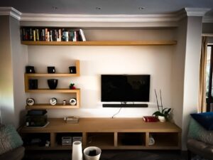 Living room cupboards with zig-zag shelf, books and TV