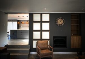 Modern Living room with grey walls, fireplace and kitchen in the background