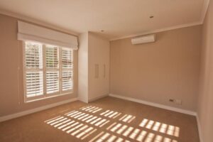 Clean bedroom with cupboards and light shining through windows